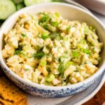 Greek yogurt egg salad in a bowl on a plate with crackers on the side.