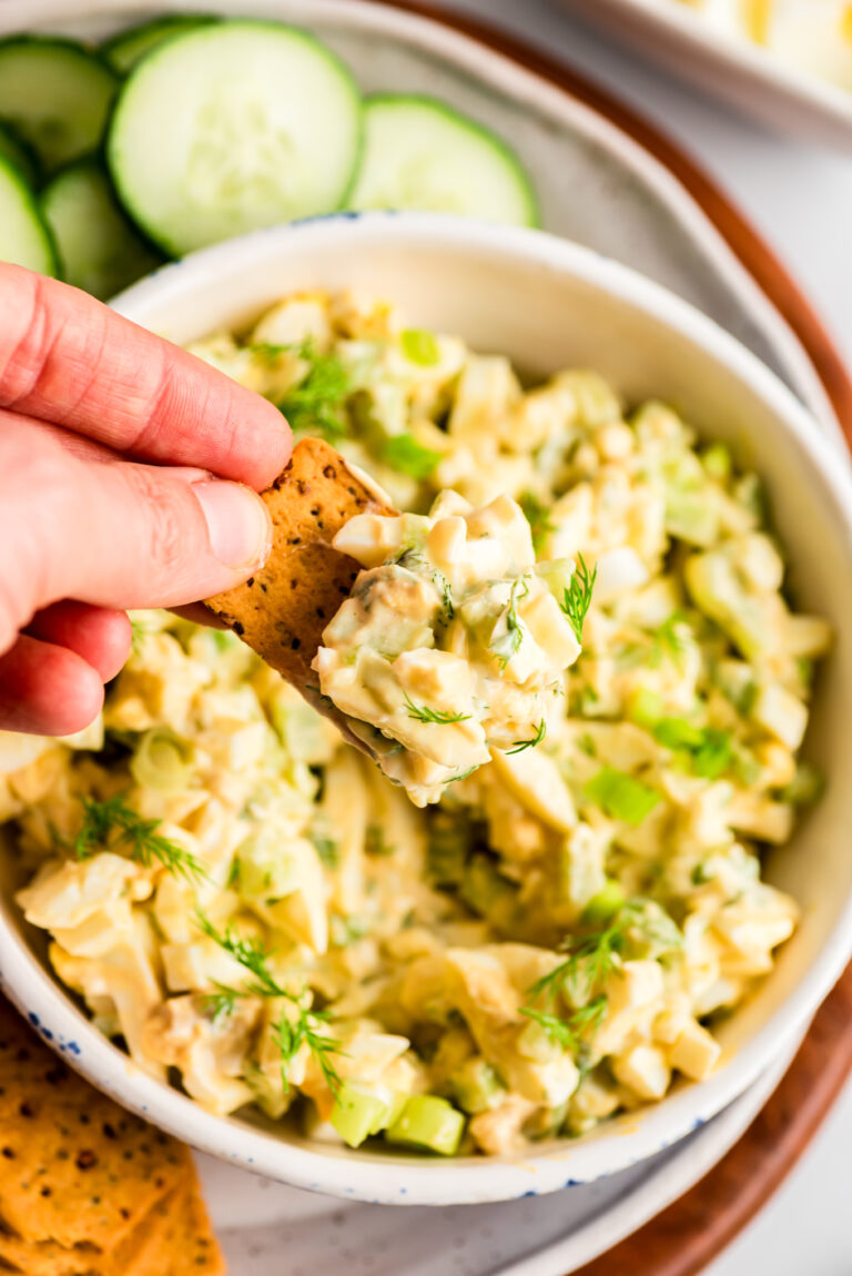 Crackers being dipped into egg salad with greek yogurt.