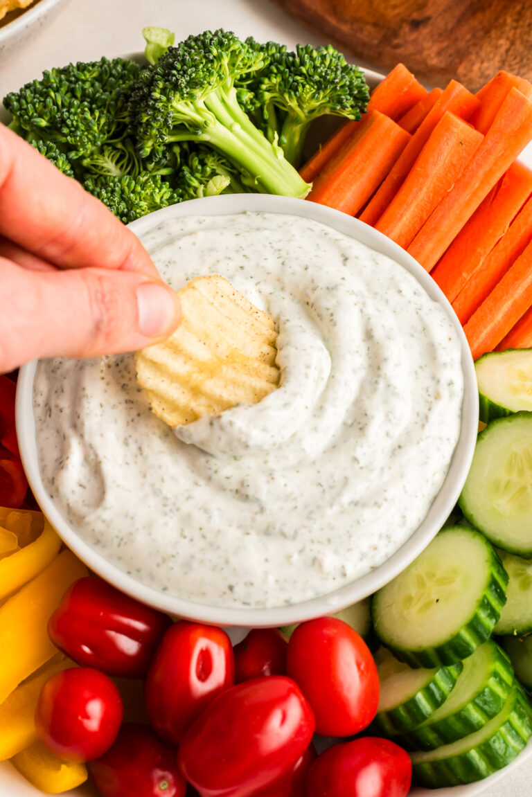 Chip being dipped in a bowl of cottage cheese ranch dip.
