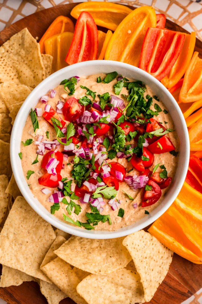 White bowl filled with cottage cheese taco dip with tortilla chips and bell peppers on the side.