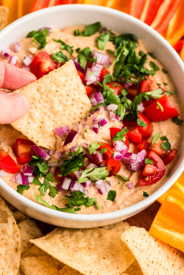 Tortilla chip being dipped in cottage cheese taco dip.