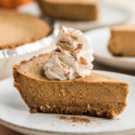 Slice of cottage cheese pumpkin pie on a white plate with whipped cream.