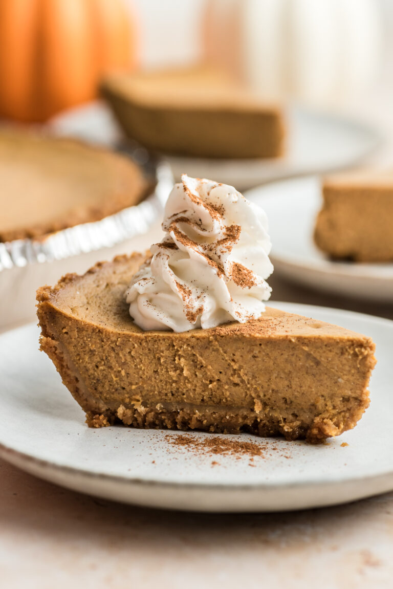 Slice of cottage cheese pumpkin pie on a white plate with whipped cream.