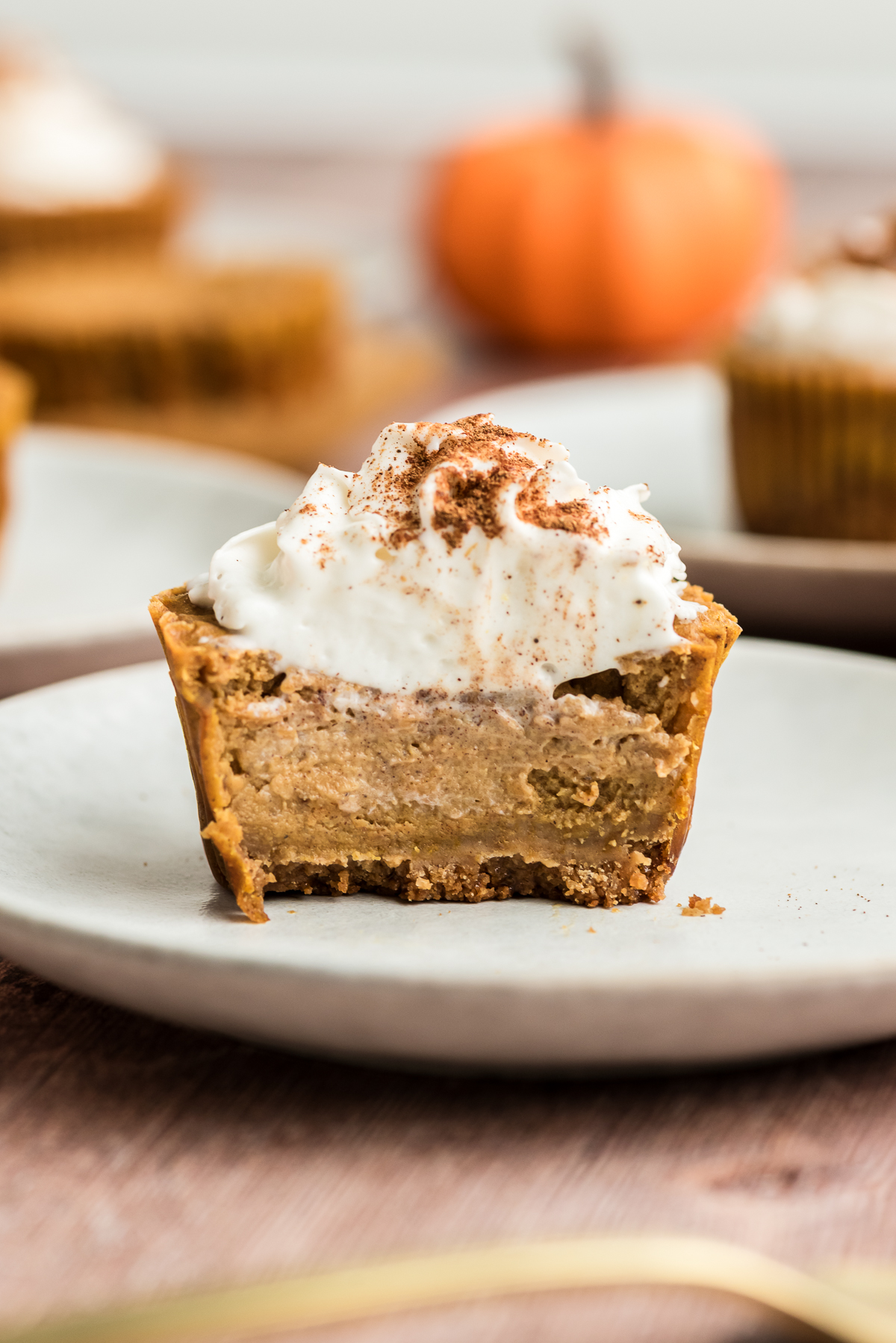 Mini protein pumpkin cheesecake with whipped cream cut in half.