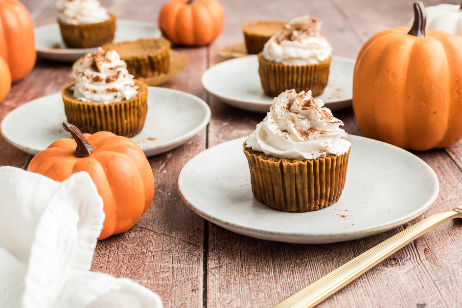 Mini pumpkin protein cheesecake with whipped cream on white plate. 