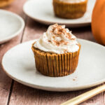 Mini pumpkin cheesecake on a white plate with whipped cream