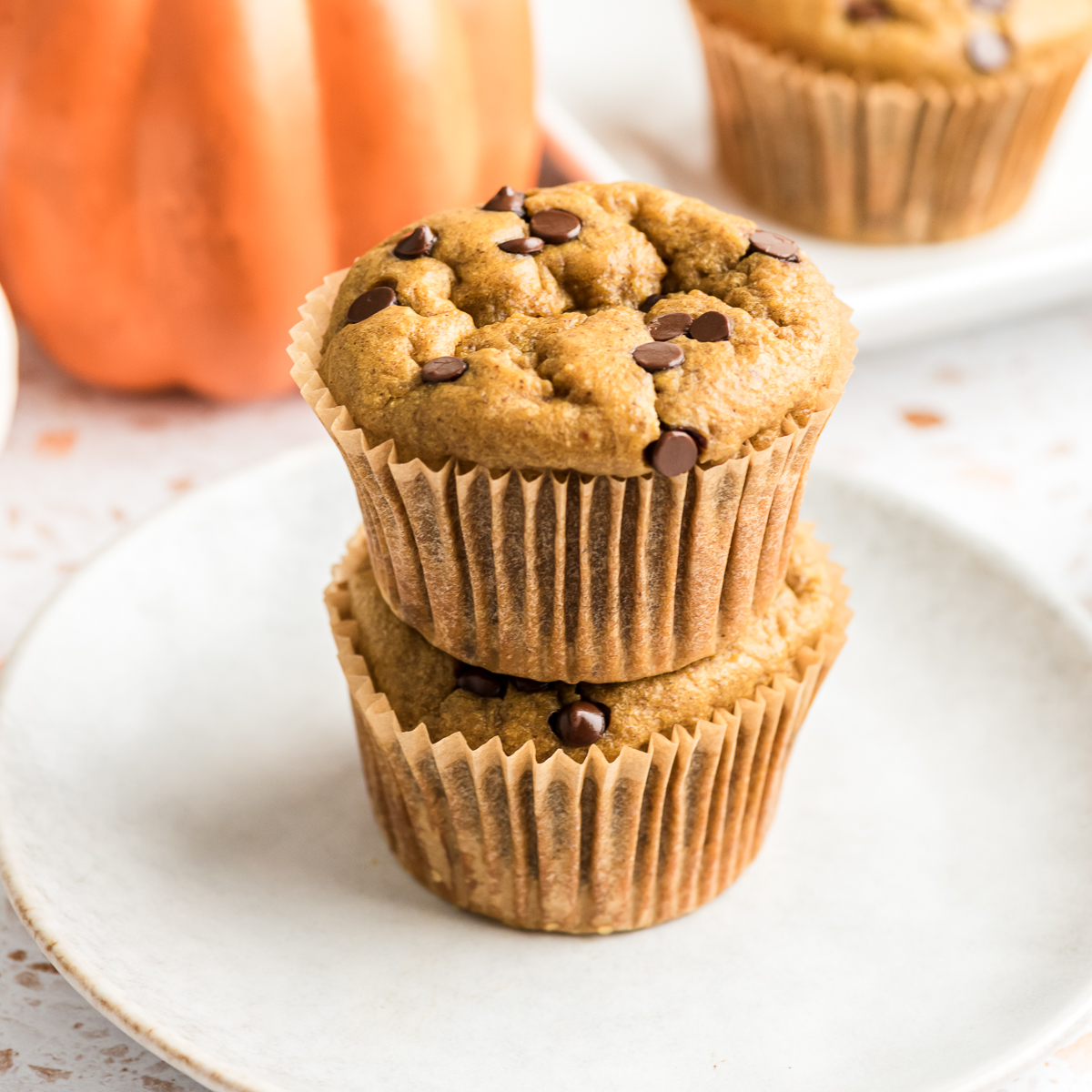 Two protein pumpkin oat muffins stacked on top of each other. 