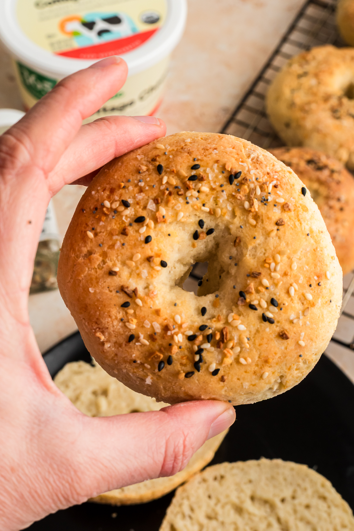 Hand holding up a cottage cheese bagel.