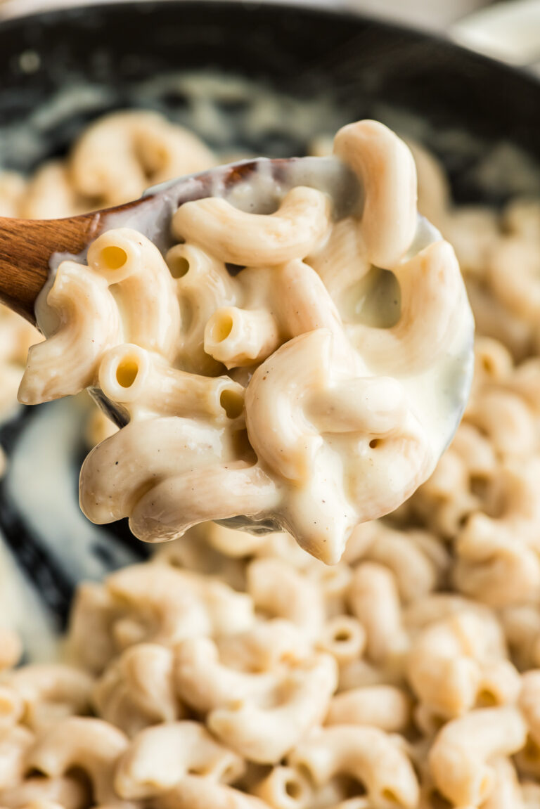 Large wooden spoon full of cottage cheese mac and cheese.