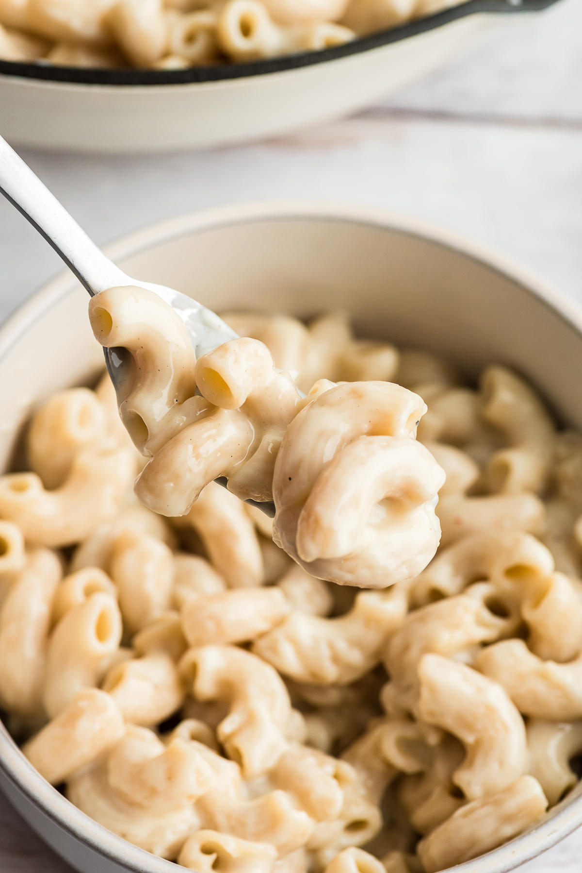 Forkful of cottage cheese mac and cheese over a bowl.