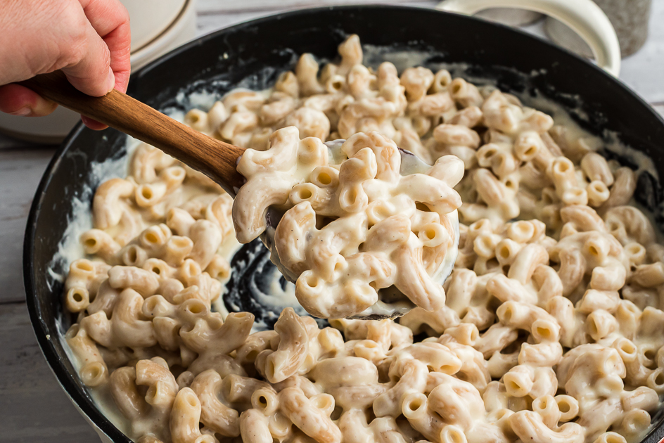 Spoonful of cottage cheese mac and cheese over a large skillet.