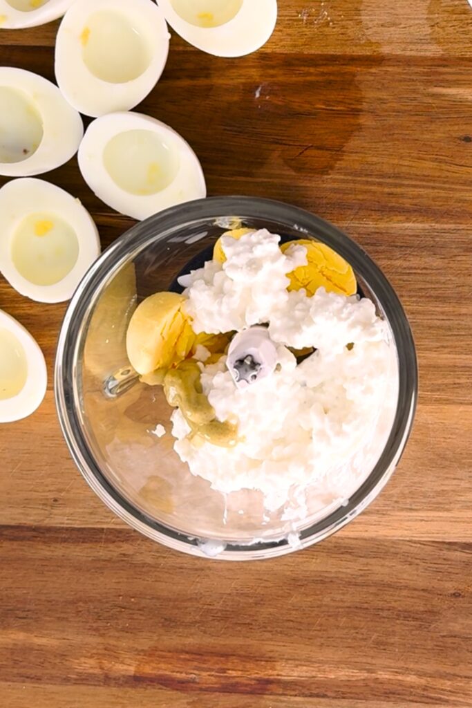 Small food processor with cottage cheese, egg yolks and dijon mustard.