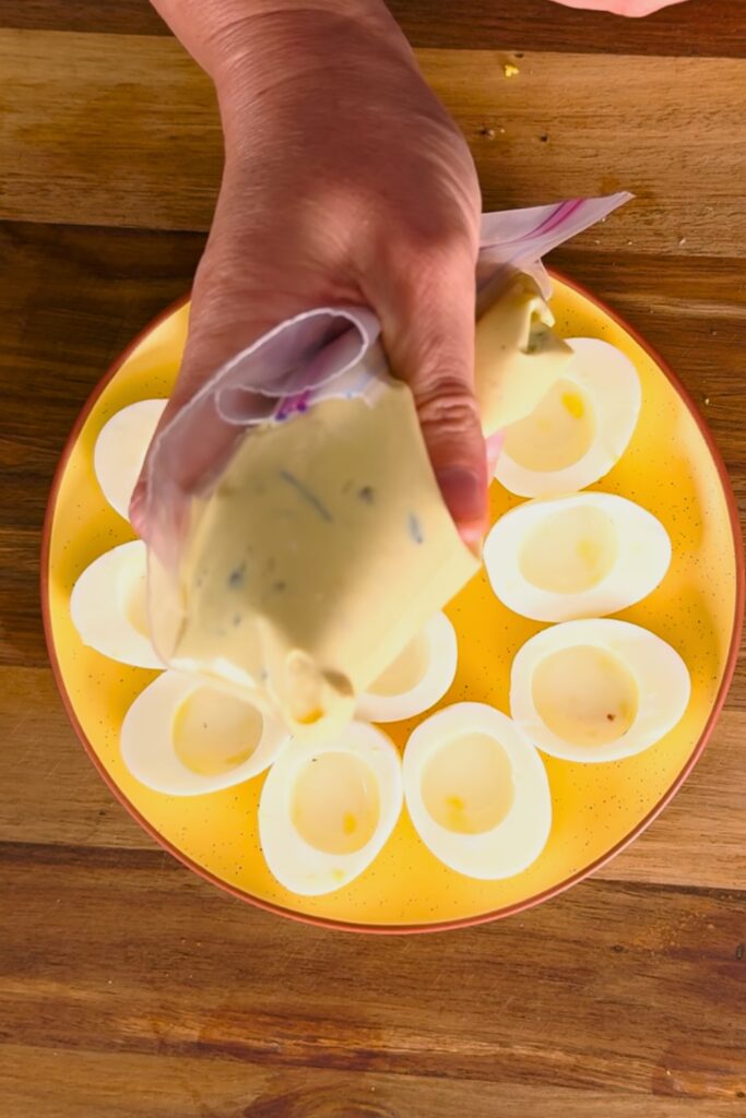 Zip lock bag with deviled egg mixture with corner cut off.