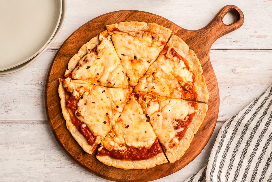 High protein cottage cheese pizza on a wood cutting board.